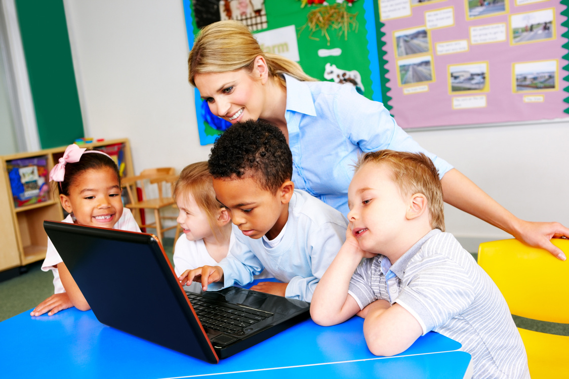 Kids using laptop computer with teacher